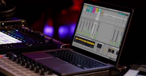 laptop displaying ableton live, next to an ableton push and arturia beatstep in a night club setting
